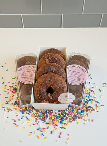 Box of chocolate donuts with clear plastic packaging on a dark surface