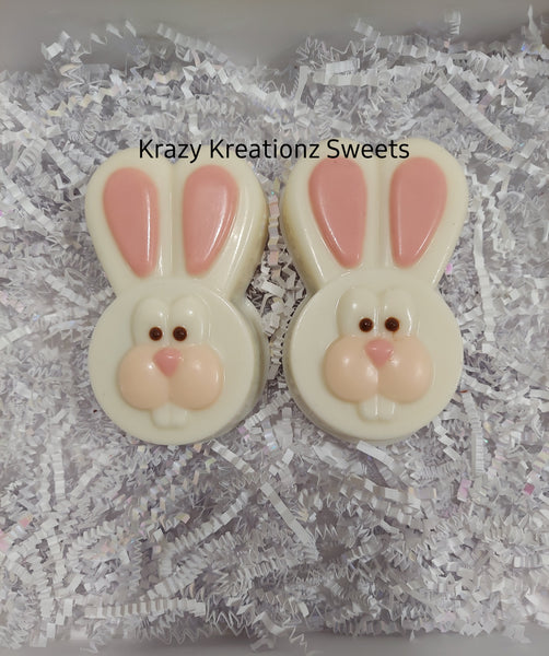 Two bunny-shaped cookies with pink ears and faces on a white paper background.